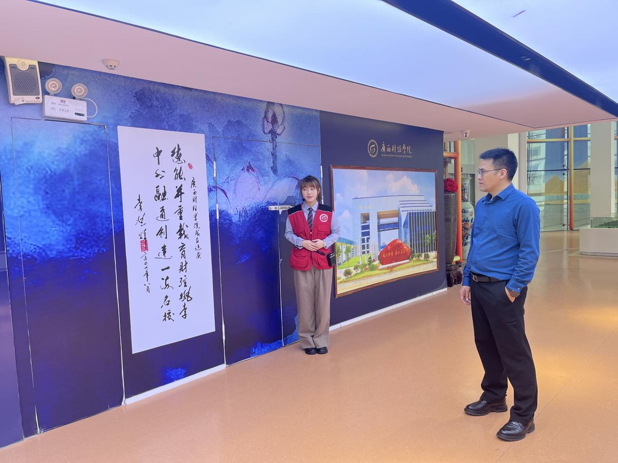 2.广西商校副校长吴天元(右一)在校史馆认真听取解说员的讲解